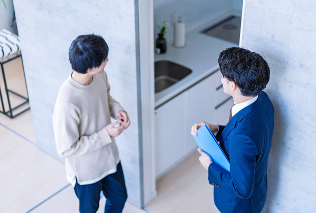 営業担当者と内見中の男性がキッチンで物件の説明をしている様子